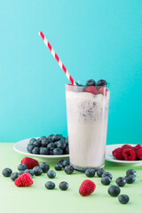 Fruit smoothie with berries served in a glass on a table with fresh raspberries and blueberries