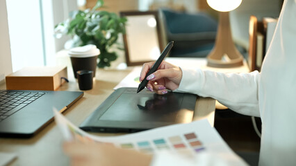 Close up of a graphic designer using a digital drawing tablet while creating artwork on a computer