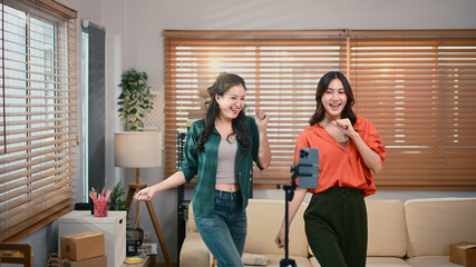 Two girl dancing and making videos for their blogs or social networks. Blogger filming vlog with online content.