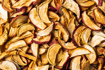 Closeup texture of mixed dried apple slices fills frame, rustic pantry ingredient for baking, tea garnish, natural snack.
