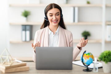 Cheerful Female Hotline Operator Wearing Headset Talking Via Video Call On Laptop Communicating...