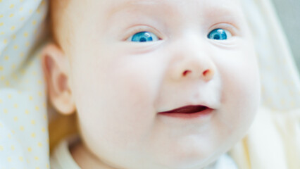 Close up portrait of the newborn boy (2 months old) with deep blue eyes in the bright white room