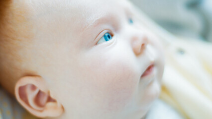 Close up portrait of the newborn boy (2 months old) with deep blue eyes in the bright white room