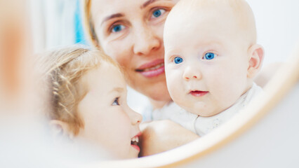 Newborn baby sees himself in the mirror for the first time. Mother shows her newborn baby a mirror magic for the first time