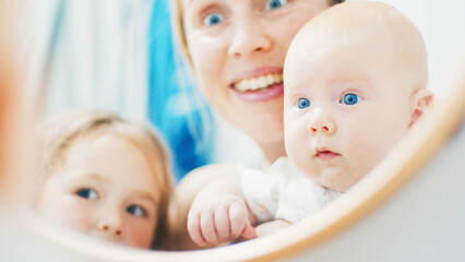 Newborn baby sees himself in the mirror for the first time. Mother shows her newborn baby a mirror magic for the first time