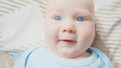 Close up portrait of the newborn boy (2 months old) with deep blue eyes in the bright white room