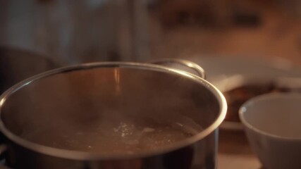 A saucepan filled with liquid noodles boils intensely on the kitchen stove, releasing steam as heat cooks the evening meal, showcasing culinary skills