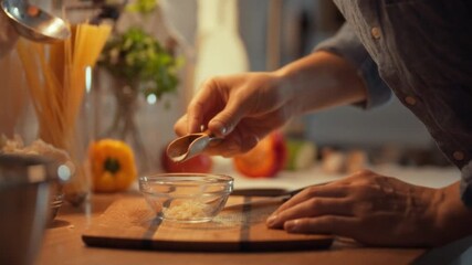 Man's hands carefully add a pinch of salty mineral crystals to a bowl containing chopped garlic, blending a savory condiment as a key ingredient for his marinade sauce, enhancing the eating experience