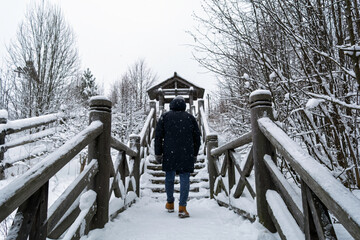 Person walking up snowy wooden stairs in winter park, quiet cold landscape with solitude mood, outdoor travel and seasonal lifestyle concept.