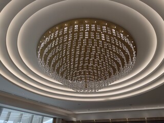 Grand Gold and Glass Chandelier with Surround Lights: Large, circular gold and glass chandelier with symmetrical lights radiating from the central fixture.