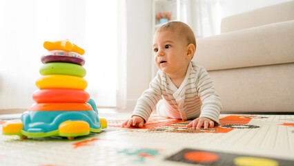 Baby playing with colorful stacking toy on mat