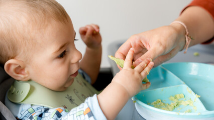 Baby learning to eat solid food with family guidance