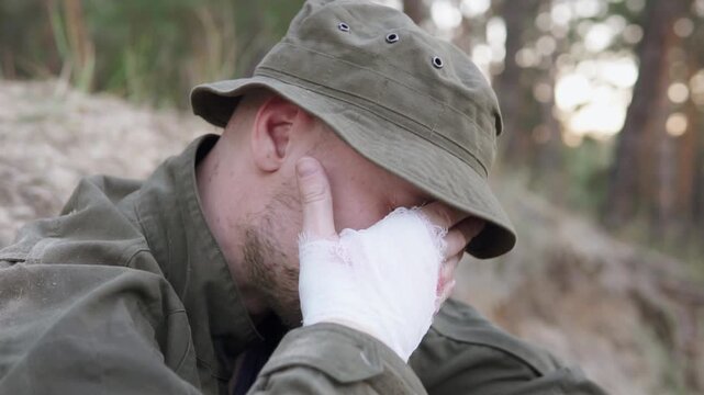 Sad soldier sitting in a trench with a bandaged hand, grieving fallen comrades. Forest setting, emotional wartime moment.