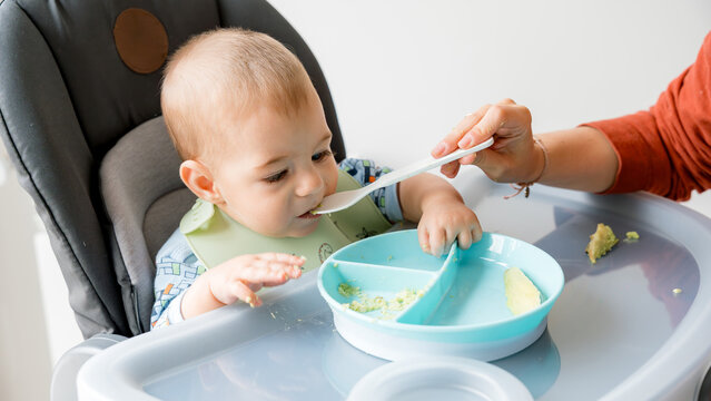 Baby learning to eat with assistance