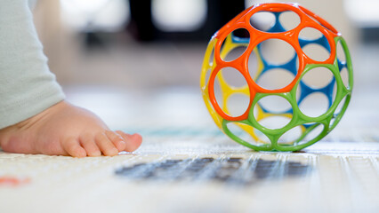 Baby's foot with colorful toy on the floor