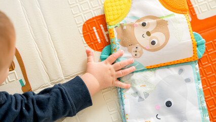 Baby playing with colorful animal-themed soft book