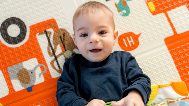 Happy baby playing on colorful playmat