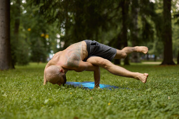 Athletic man controlling core stability amidst lush greenery