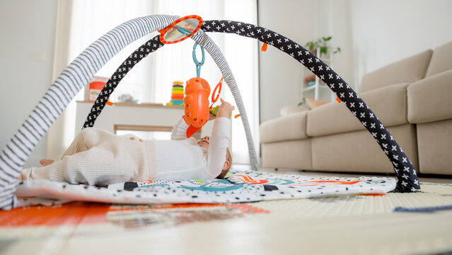 Baby playing on colorful playmat with toys
