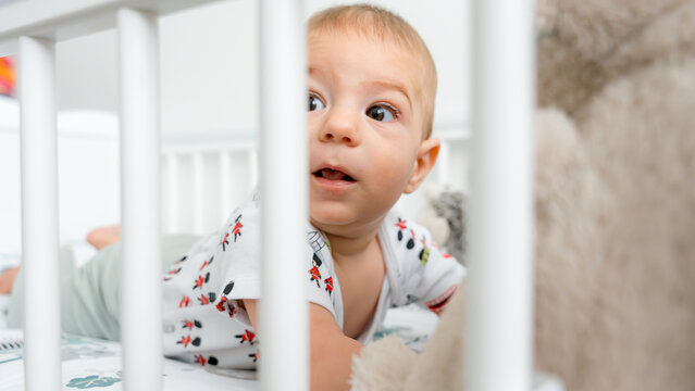 Curious five month old baby in white crib