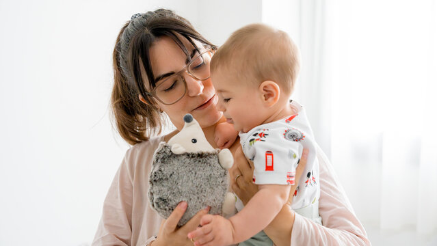 Mother holding baby with toy hedgehog