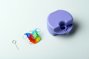 Orthodontic dental retainer with storage case and key on light blue background, removable appliance care concept for hygiene, storage, and orthodontic use.