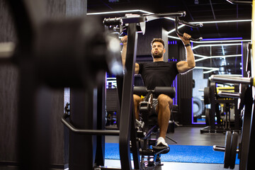 Strong man using lat pulldown machine for upper body workout in modern gym