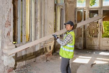 Focused worker in safety gear assesses measurement by sunlit arched window