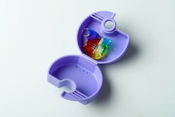 Open purple retainer case holds colorful orthodontic plate on light background, ready for daily storage and hygienic care.