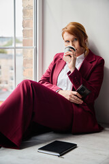 Redheaded executive contemplating with coffee and urban background scenes