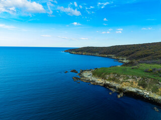 Coastline view of the sea and cliffs in a quiet location during midday under clear blue sky