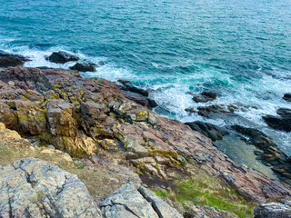 Waves crashing against rocky shore at coastal location during daylight showing natural landscape and water movement