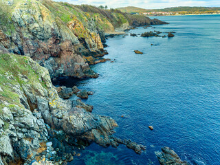 Coastline view showing rocky cliffs and clear waters along the shore in a natural landscape during daytime with visible land in the background