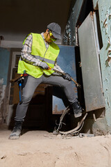 Construction worker operating jackhammer in derelict interior