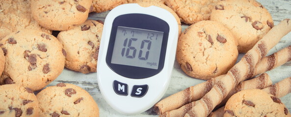Glucometer with high sugar level and cookies. Healthy nutrition and reduction eating sweets during diabetes