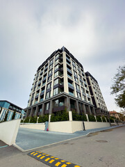Modern apartment building stands tall in urban area with surrounding road and clear sky in the background