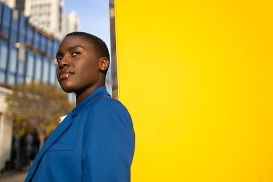 Confident businesswoman in blue suit against yellow