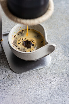 Fresh espresso pouring into gray ceramic cup