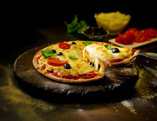 Pizza mit herausgeschnittenem Slice mit Oliven und viel K&auml;se auf rustikalem runden Brett