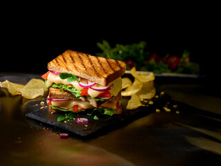 Sandwich mit geschmolzenem K&auml;se roten Zwiebeln Tomatenscheiben und Salat auf Schieferplatte