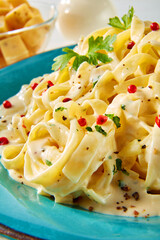  Tagliatelle mit K&auml;se Pfeffer Sauce auf t&uuml;rkis farbigen Teller