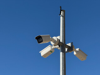Security cameras installed on a metal pole against clear blue sky background