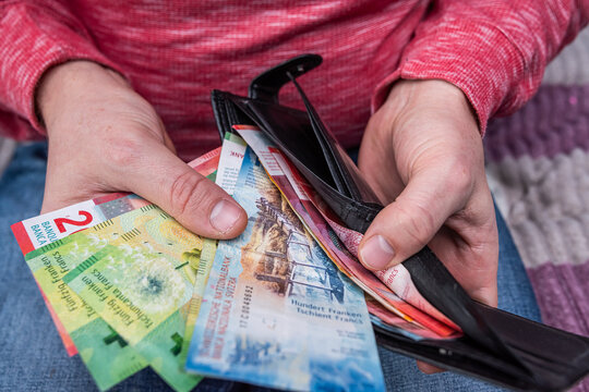 Swiss franc banknotes held in hands with black wallet