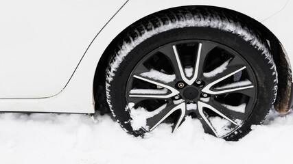 Car wheel and tire in snow in winter