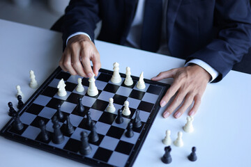 Businessman playing chess game; business strategy, leadership and management concept.