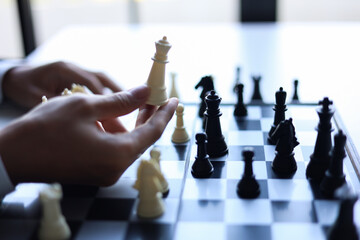 Businessman playing chess game; business strategy, leadership and management concept.