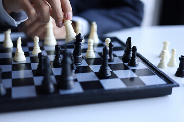 Businessman playing chess game; business strategy, leadership and management concept.