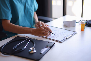 Doctor at desk reading a patient file,&nbsp;analyzing a patient's medical history, test results, or diagnosis to determine the best course of treatment.