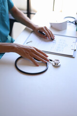 Doctor at desk reading a patient file,&nbsp;analyzing a patient's medical history, test results, or diagnosis to determine the best course of treatment.