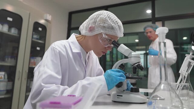 Scientist examines samples under microscope in research lab in the evening